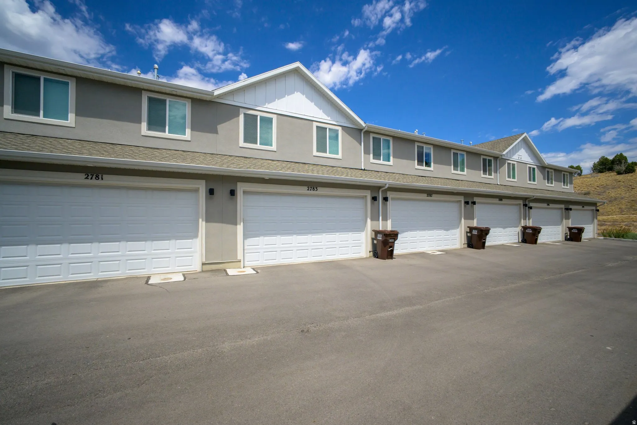 Multi-unit property with a row of individual attached garages featuring white paneled garage doors