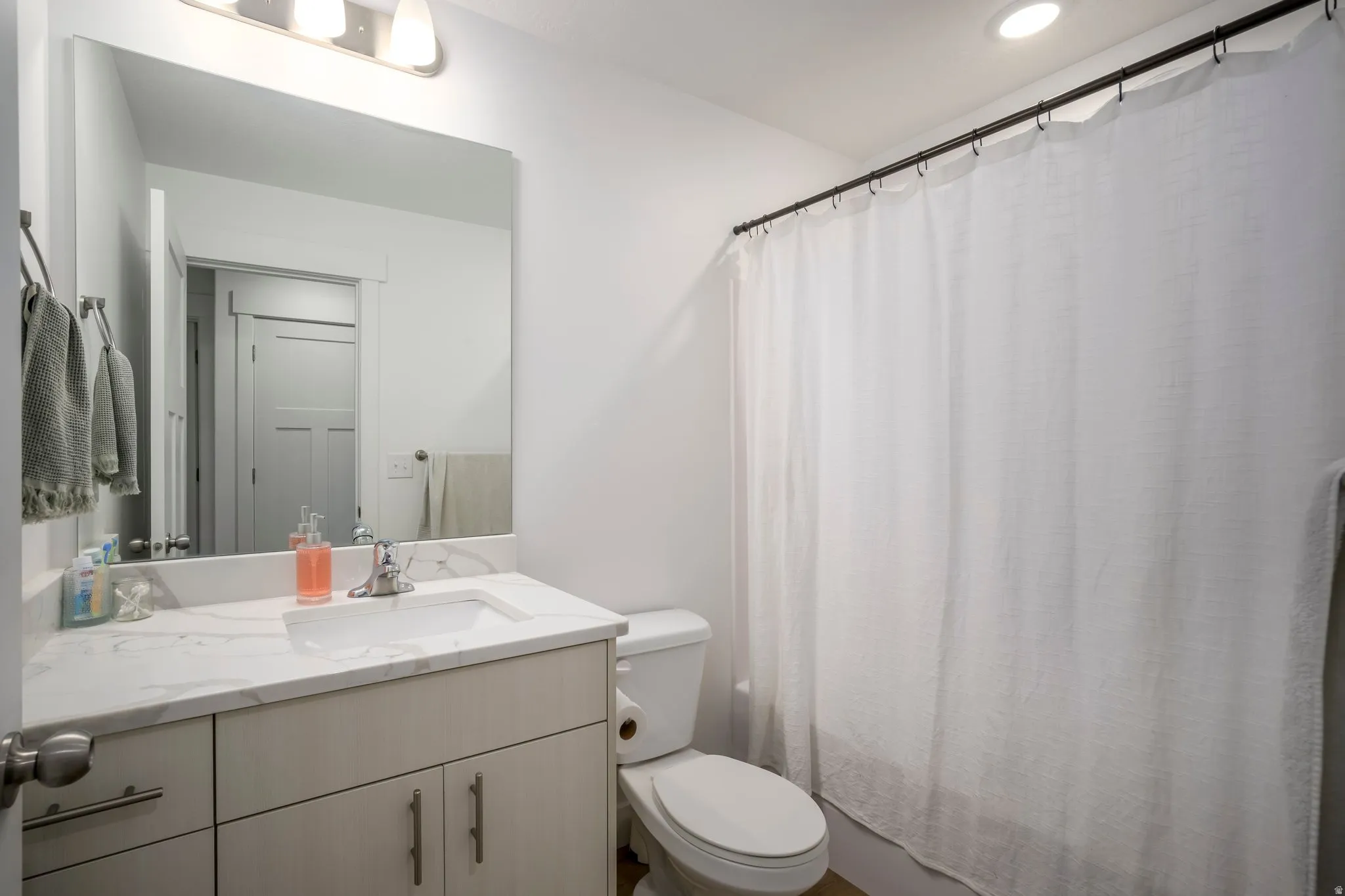 Bathroom featuring a large vanity with an integrated sink and light-toned cabinetry, a white countertop, and a wide mirror