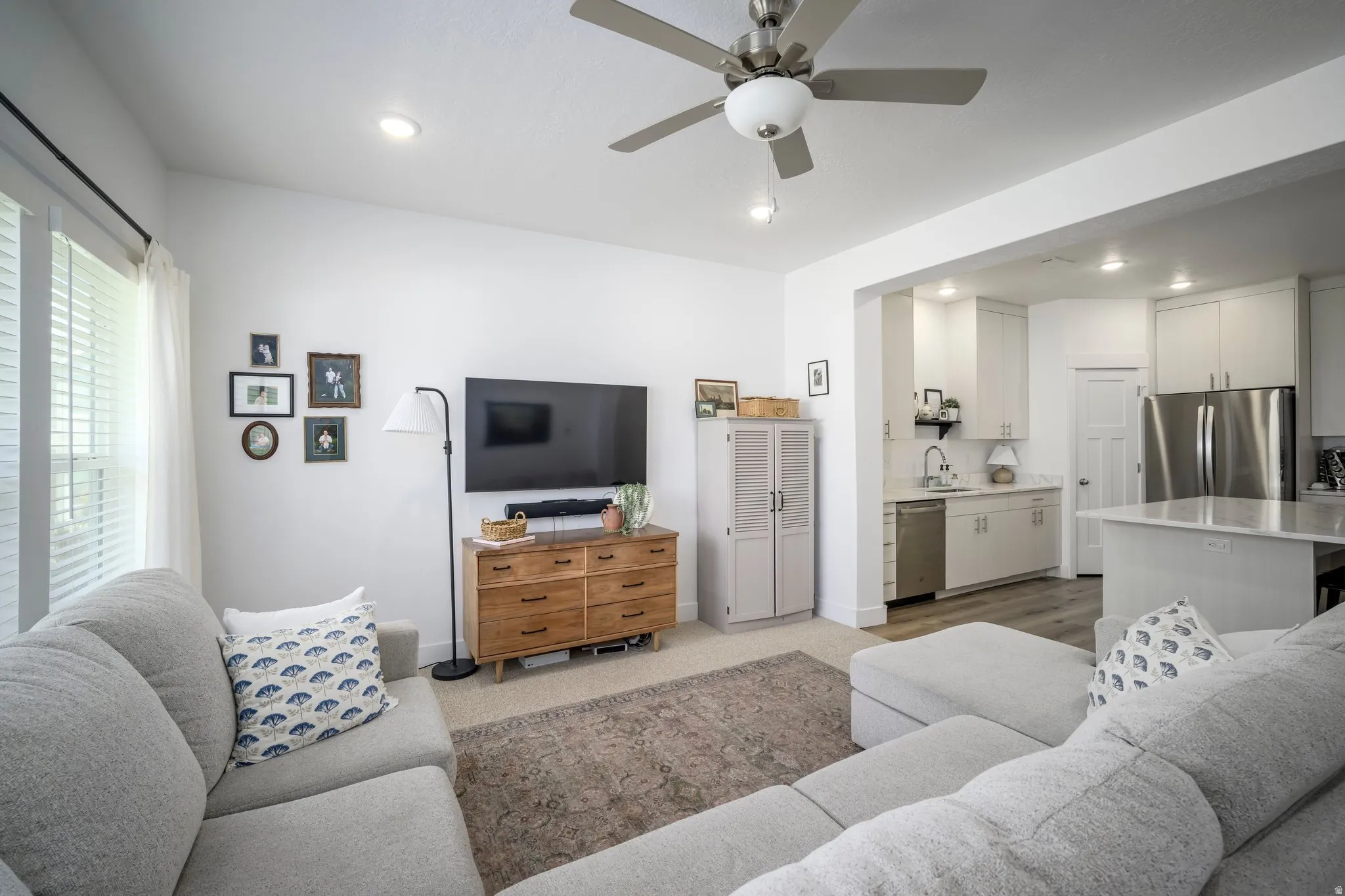 Open-concept living area featuring a ceiling fan with light, recessed lighting, and a view into the kitchen