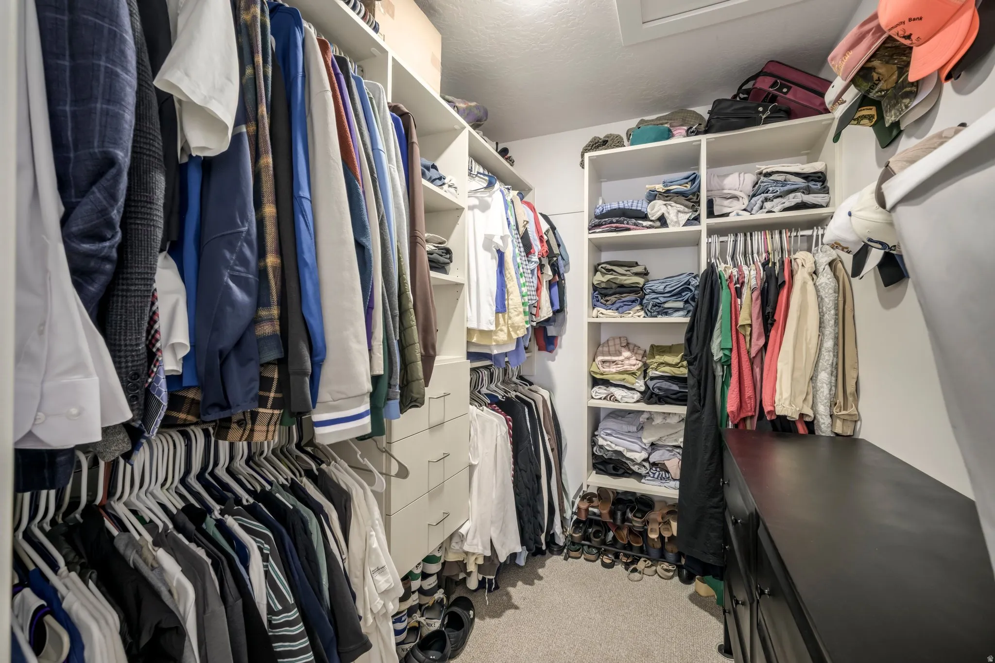 Primary bedroom Walk-in closet featuring built-in shelving, multiple hanging rods, integrated drawers, and carpeted flooring