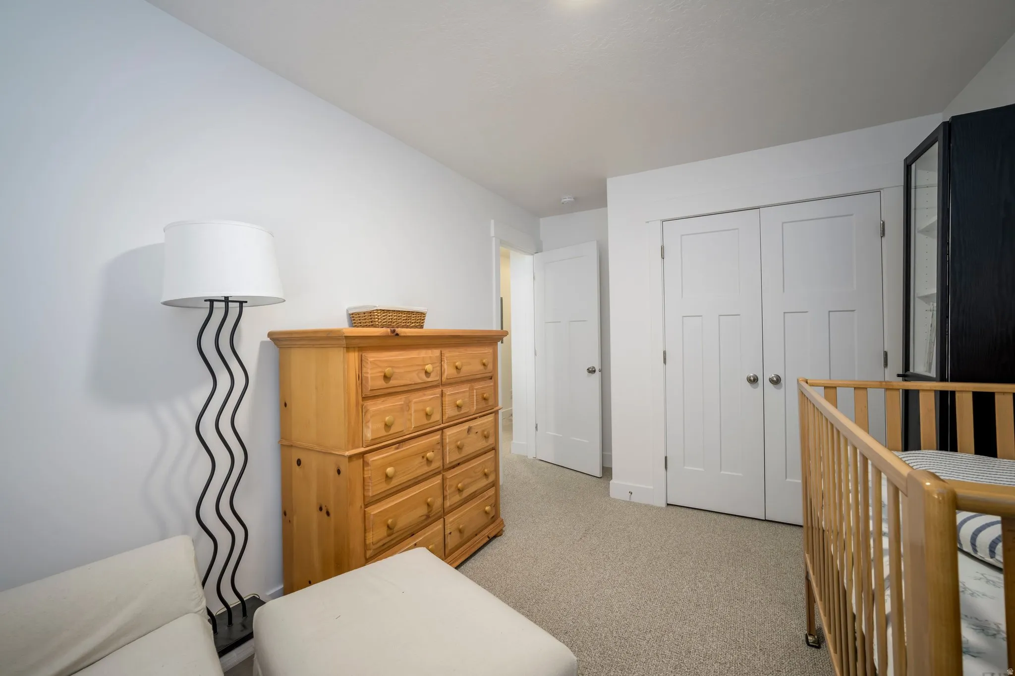 Carpeted interior space featuring white walls and a pair of two-panel doors with brushed nickel hardware