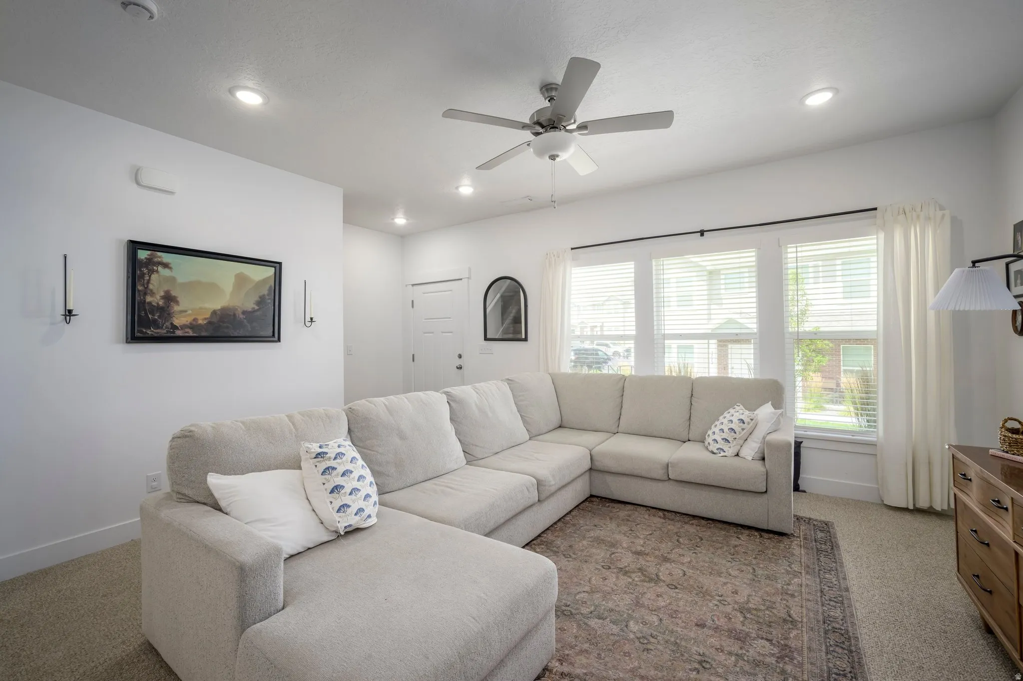 Living area featuring recessed lighting, a ceiling fan, carpet flooring, and multiple windows with blinds and curtains