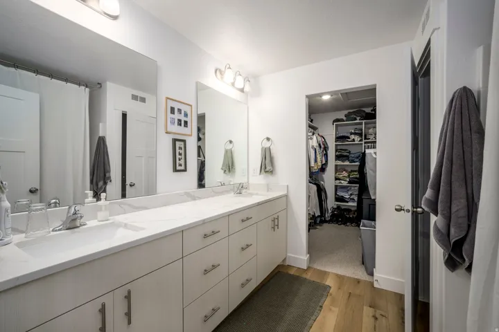 Primary Bathroom featuring a long dual vanity with light-toned cabinetry and a light-toned countertop, set against a white wall