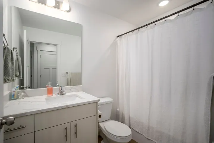 Bathroom featuring a large vanity with an integrated sink and light-toned cabinetry, a white countertop, and a wide mirror