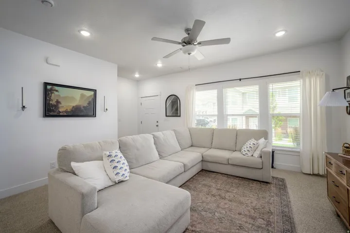 Living area featuring recessed lighting, a ceiling fan, carpet flooring, and multiple windows with blinds and curtains