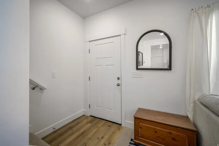 Entryway featuring light wood-finish flooring, white walls, and a white paneled door with brushed nickel hardware