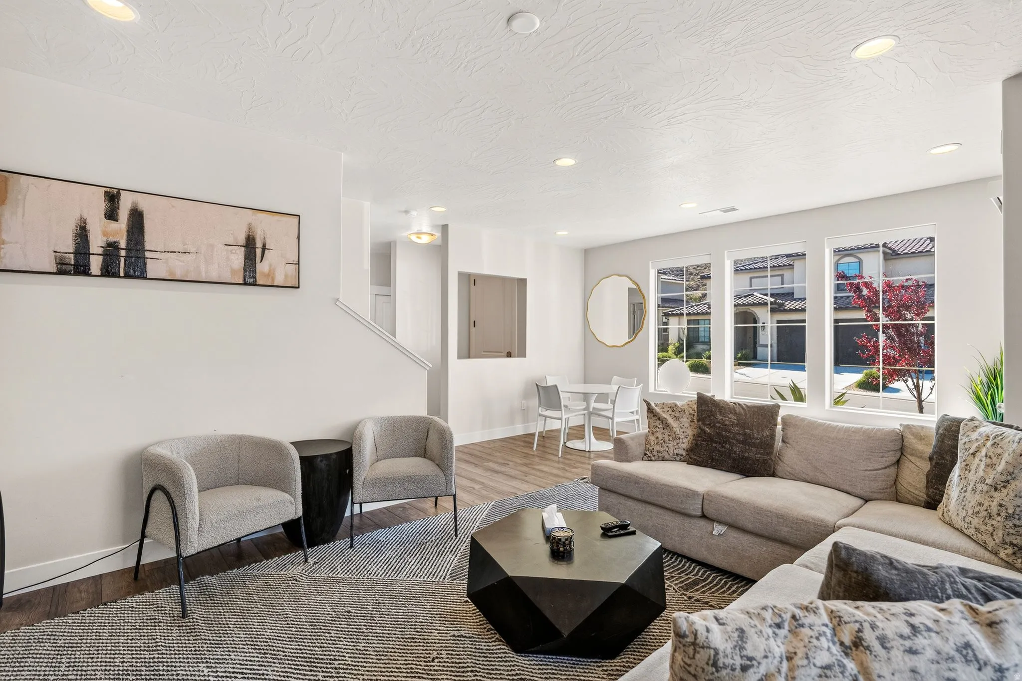 Open-concept living area with wood-finish flooring, recessed lighting, and multiple large windows