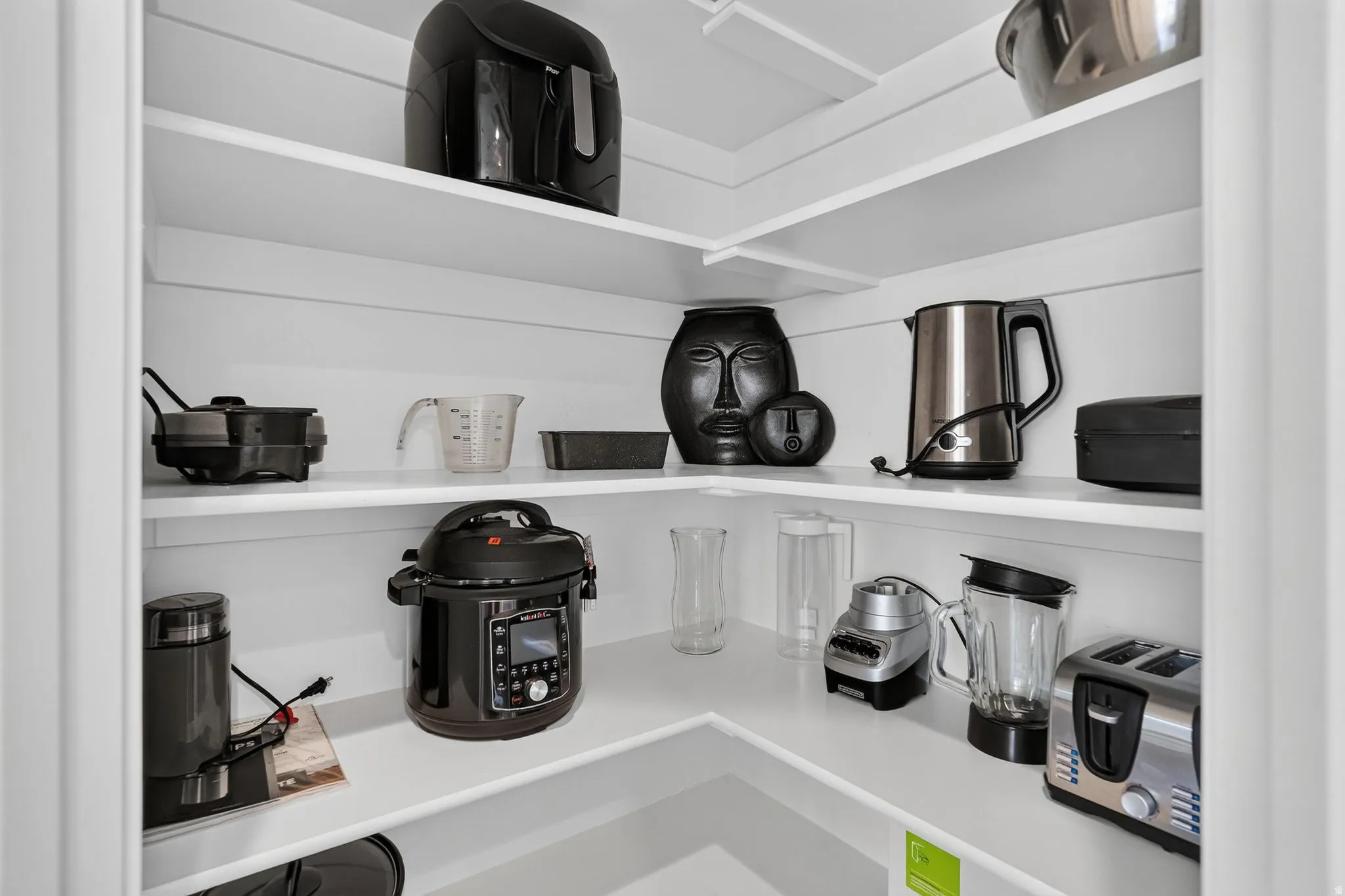 Corner pantry featuring multiple white shelves