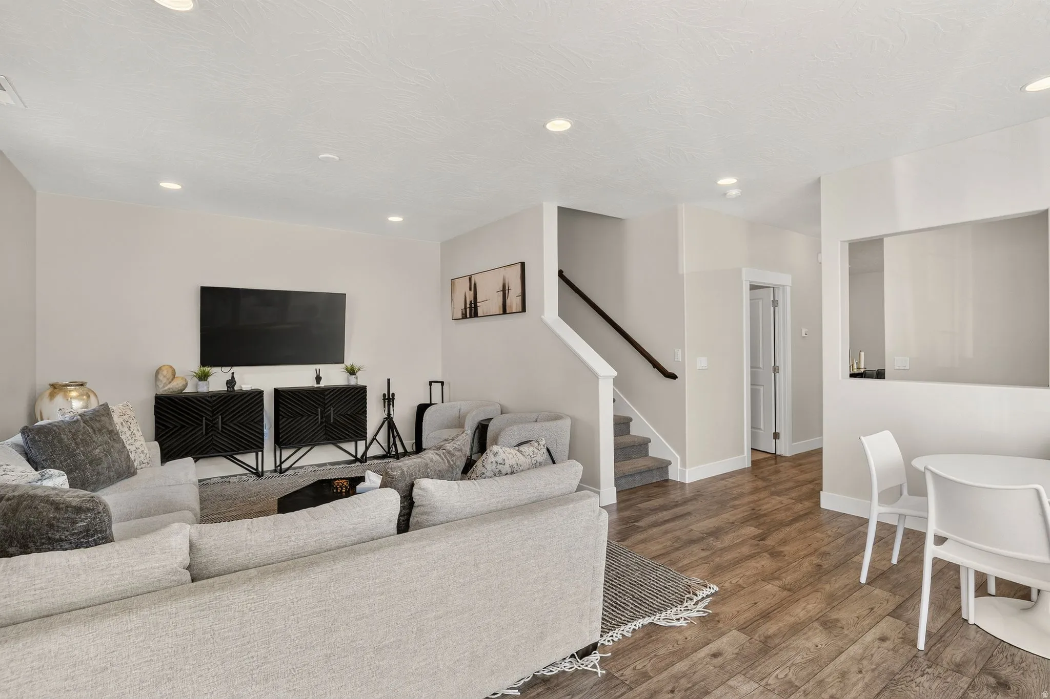 Expansive living area with wood-finish flooring, recessed lighting, and a neutral color palette