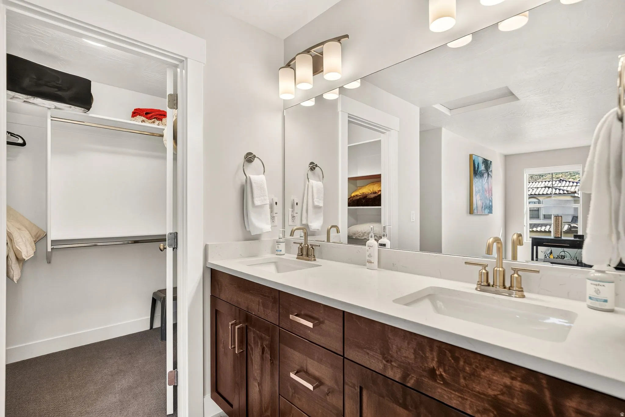 Dual vanity featuring wood-finish cabinetry, white countertops, and undermount sinks