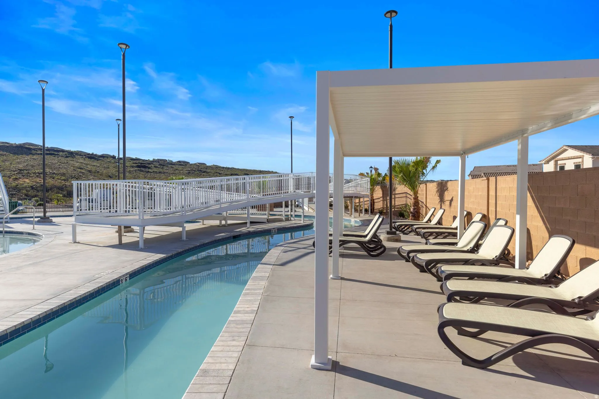 Concrete patio with an overhead pergola, a leisure pool, and a white accessible ramp