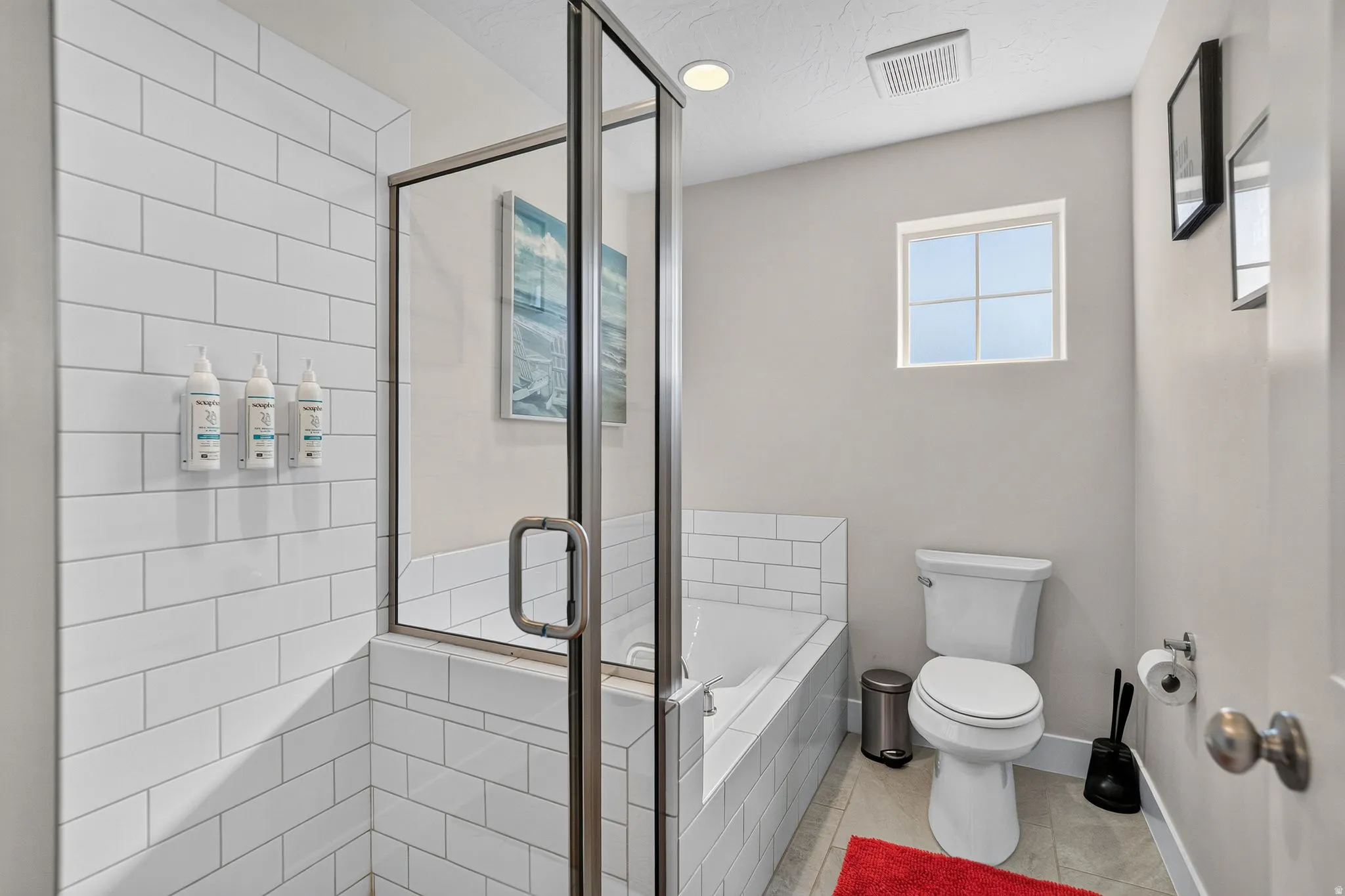 Full bathroom featuring a glass-enclosed shower, built-in soaking tub, subway tile surround, and a privacy window