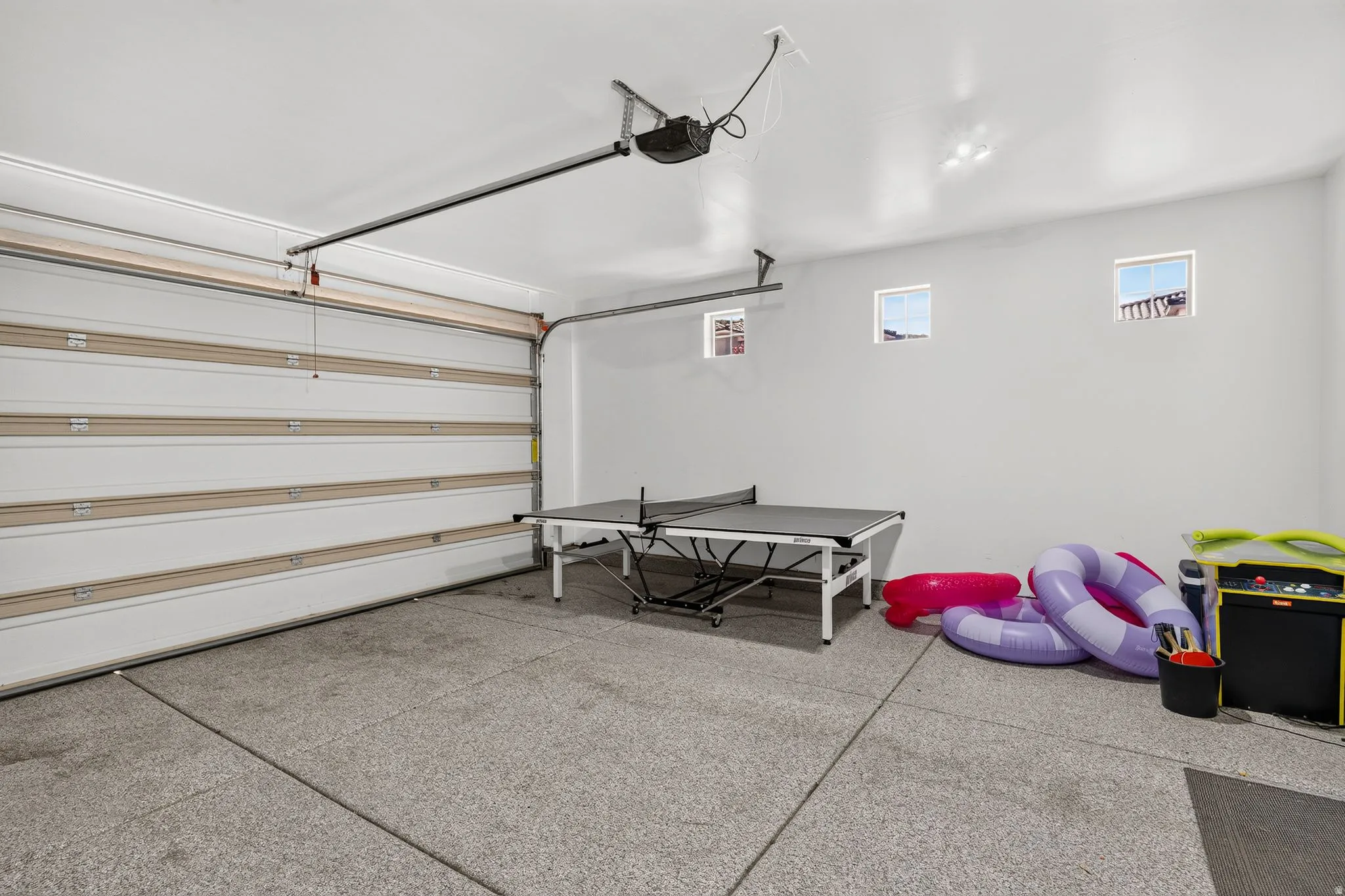 Spacious garage featuring a sectional overhead door, three transom windows, an automatic door opener, and durable epoxy flooring