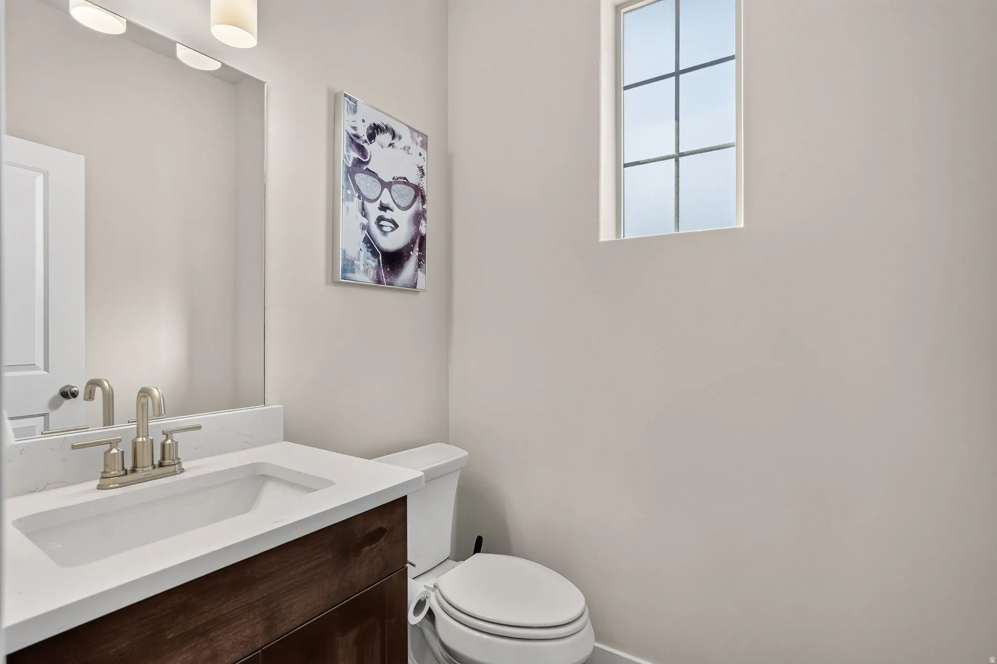 Bathroom vanity with a white countertop and an undermount sink, complemented by a brushed nickel faucet