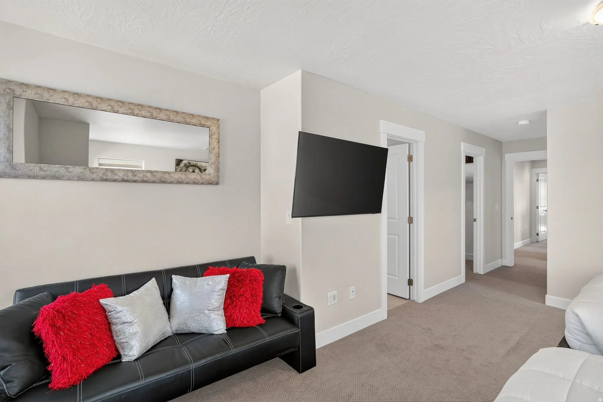 Hallway featuring a wall-mounted television, neutral wall paint, and white trim