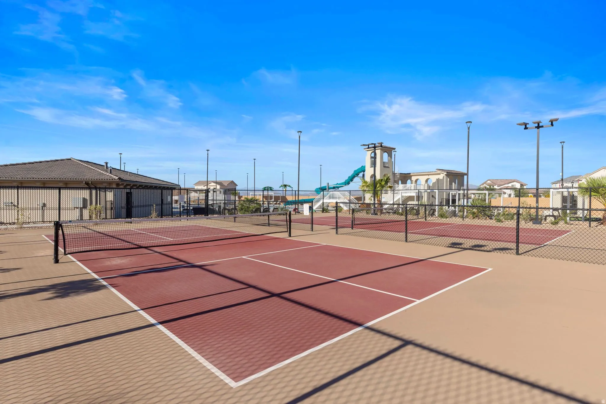 Two fenced hard courts with red and tan surfacing