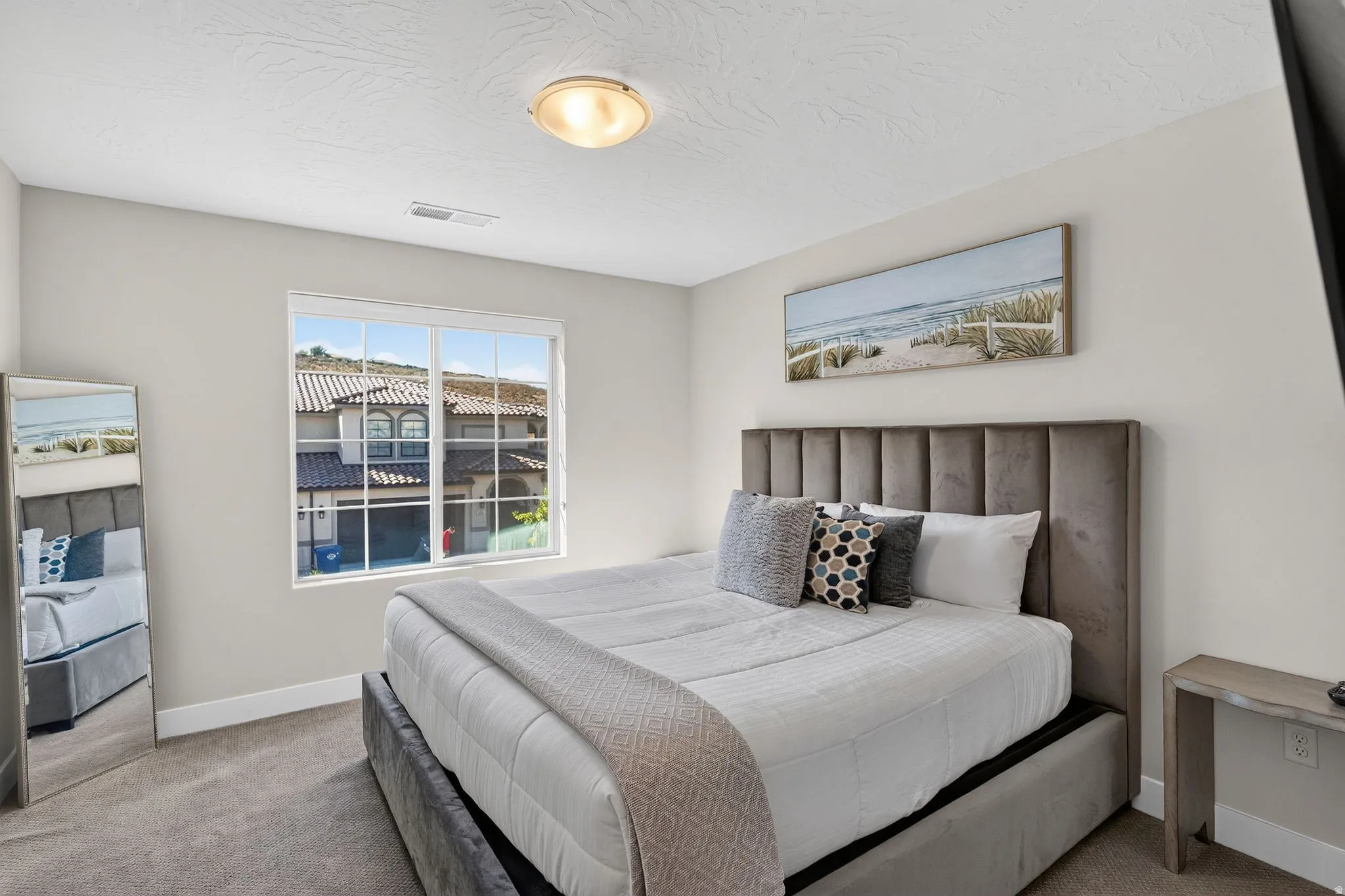 Neutral toned bedroom featuring a window with exterior residential views, recessed lighting, and carpet flooring