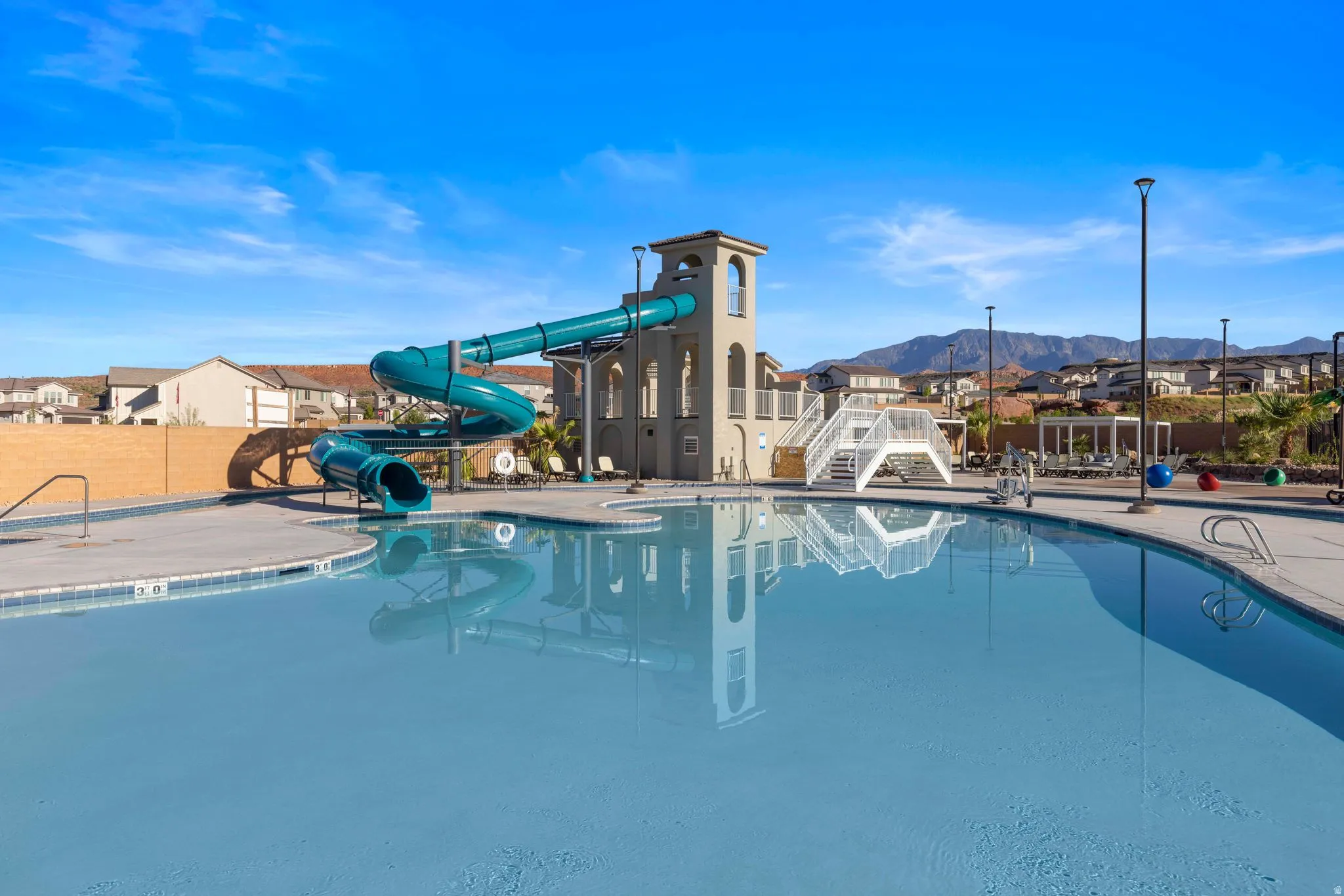 Expansive community pool with a large water slide structure and tower