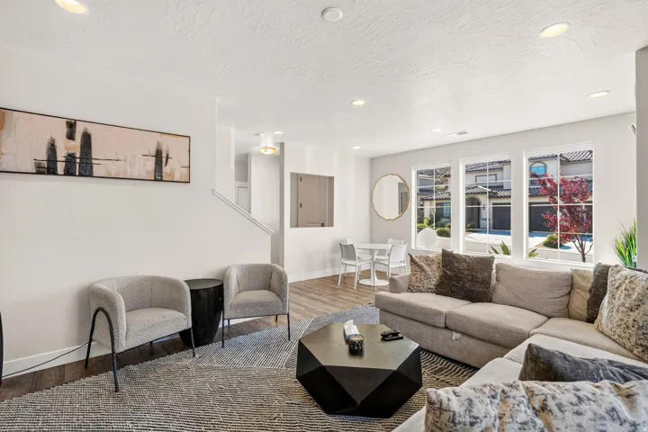 Open-concept living area with wood-finish flooring, recessed lighting, and multiple large windows