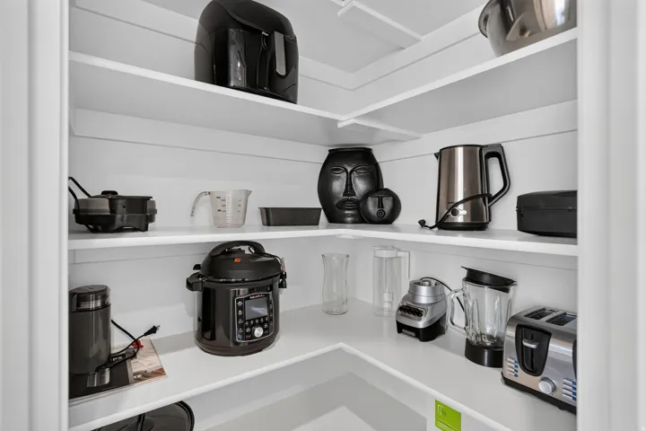 Corner pantry featuring multiple white shelves