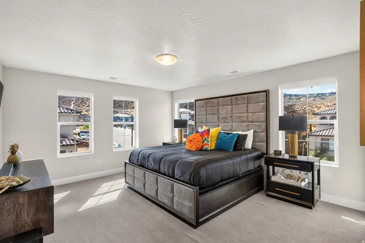 Spacious bedroom featuring light-toned walls, multiple double-hung windows, and light gray carpeting