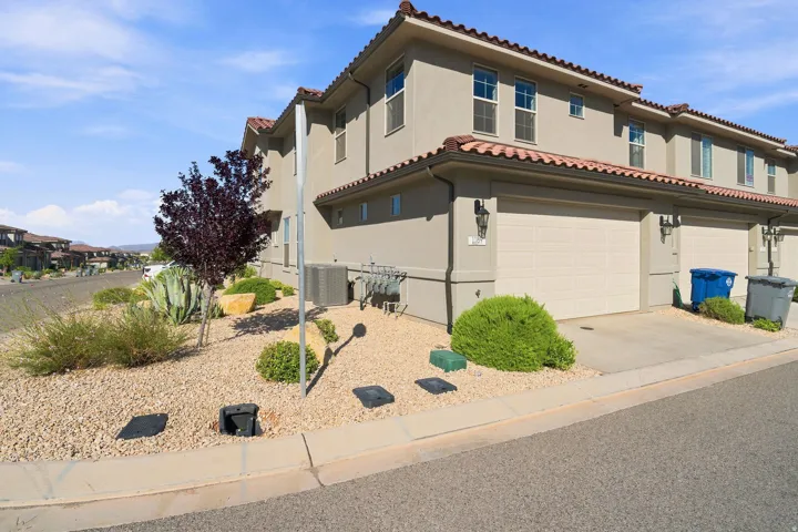 Stucco exterior featuring dual garages, red tile roofing, and desert landscaping