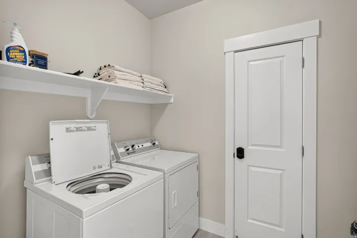 Dedicated laundry area featuring a white floating shelf, neutral wall color, and light wood-finish flooring