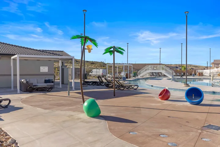 Outdoor splash pad area featuring decorative palm tree-shaped water features, a shaded lounging area, and dedicated seating