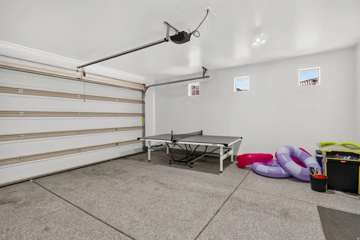 Spacious garage featuring a sectional overhead door, three transom windows, an automatic door opener, and durable epoxy flooring