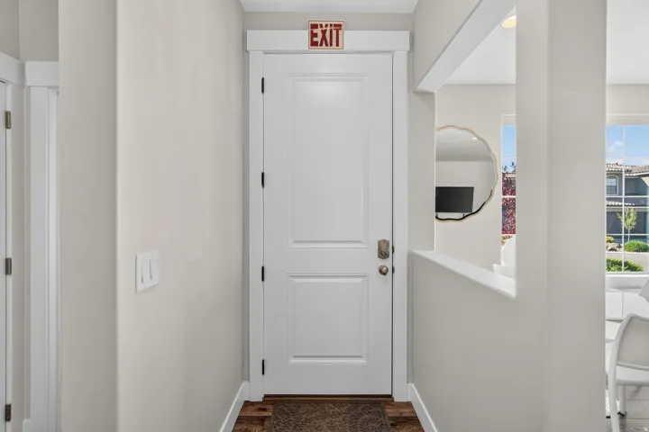 Entryway featuring a paneled door with white trim, wood-finish flooring, and a decorative wall cutout