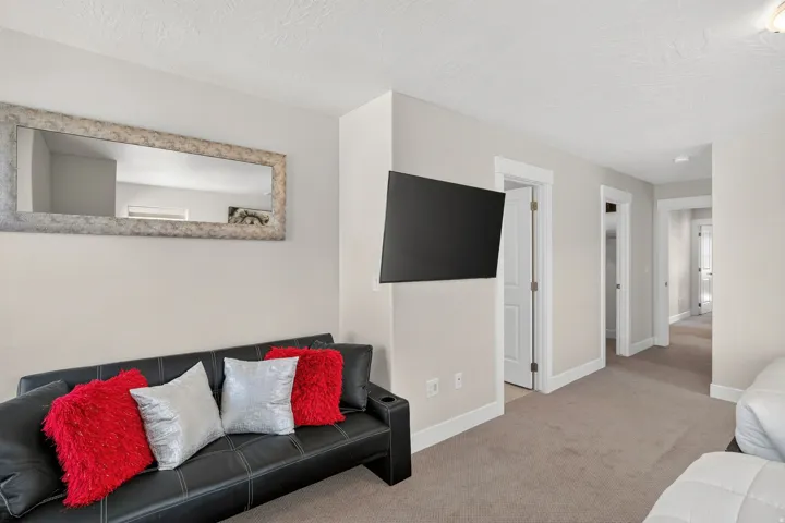 Hallway featuring a wall-mounted television, neutral wall paint, and white trim
