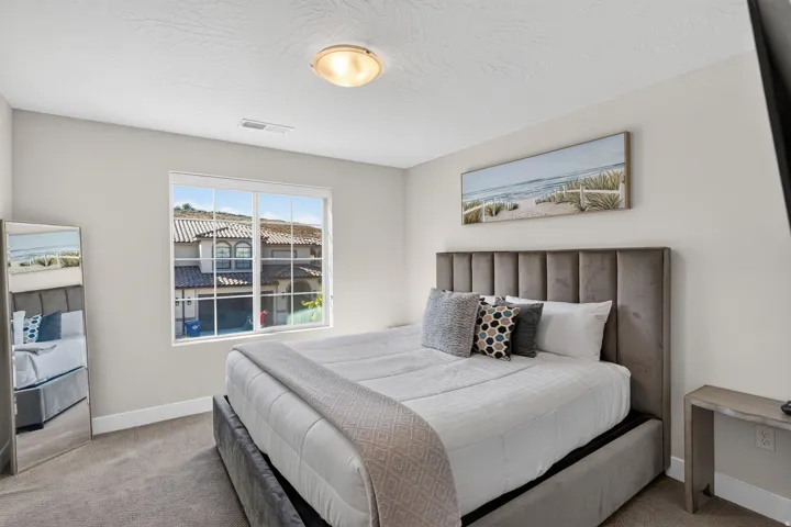 Neutral toned bedroom featuring a window with exterior residential views, recessed lighting, and carpet flooring