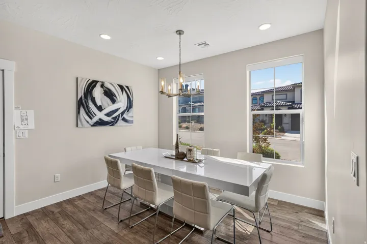 Dining area featuring wood-finish flooring, two large windows, a modern chandelier, recessed lighting, and crisp white baseboards