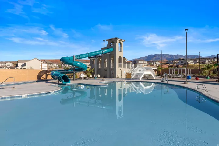 Expansive community pool with a large water slide structure and tower