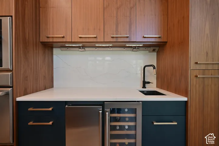 Contemporary wet bar featuring wood-grain cabinetry and dark blue lower cabinets