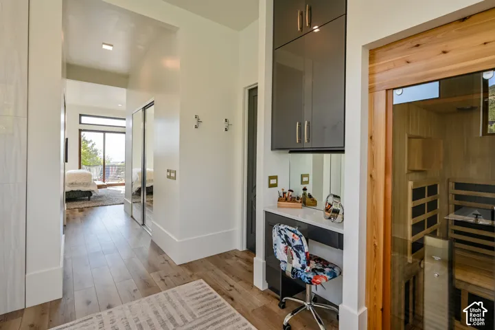 Light wood-finish flooring extending through a hallway with white walls