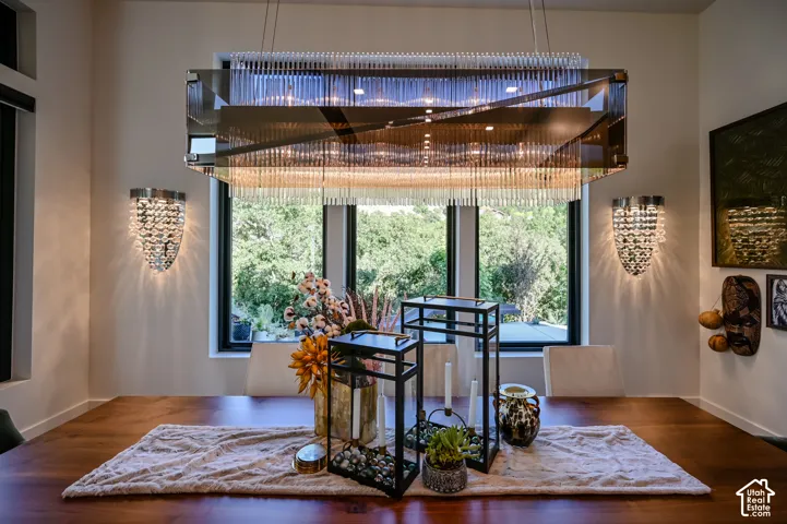 Dining area featuring a rectangular chandelier with clear glass rods, two crystal-style sconces, and a dark wood-finish table
