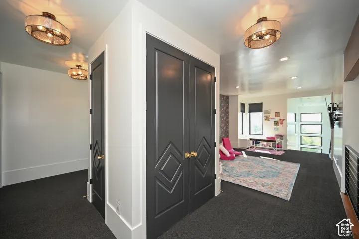Hallway featuring dark gray carpet flooring, recessed lighting, and modern ceiling fixtures