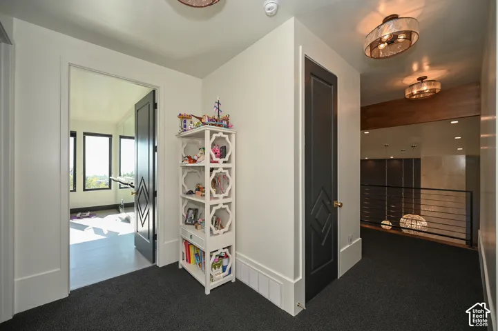 Upper-level hallway with dark gray carpet, white walls, and contemporary ceiling light fixtures
