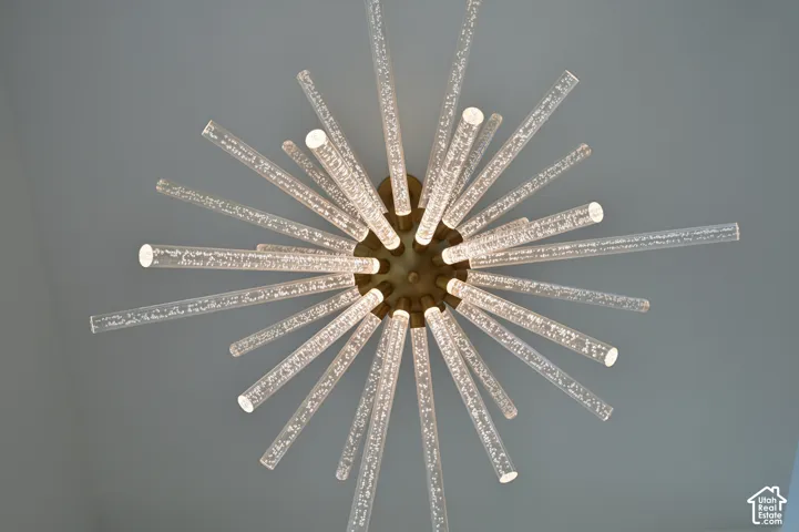 Contemporary chandelier featuring multiple radiating glass rods with internal bubble detailing, mounted on a central bronze-toned fixture against a smooth ceiling