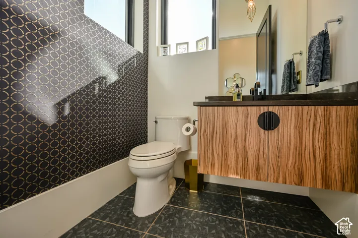 Floating wood-finish vanity with a dark countertop and a wall-mounted faucet