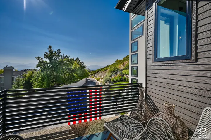 Upper-level balcony featuring horizontal slat railing, gravel flooring, and mountain scenery
