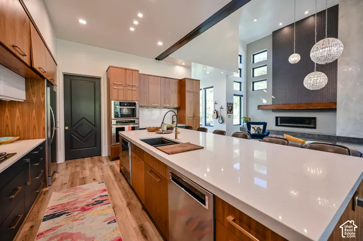 Open-concept kitchen featuring a spacious island with a light-toned countertop, integrated sink, and stainless steel dishwasher