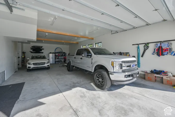 Spacious garage featuring a concrete floor, bright overhead lighting, exposed ceiling joists, and multiple storage options