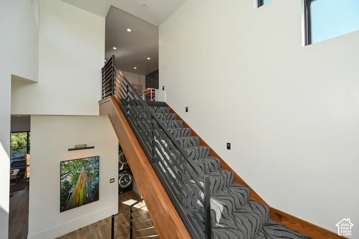 Modern staircase featuring wood-finish treads, a patterned carpet runner, and metal railings
