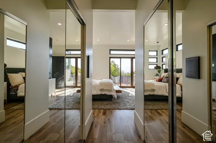 Hallway with wood-finish flooring, recessed lighting, and mirrored closet doors