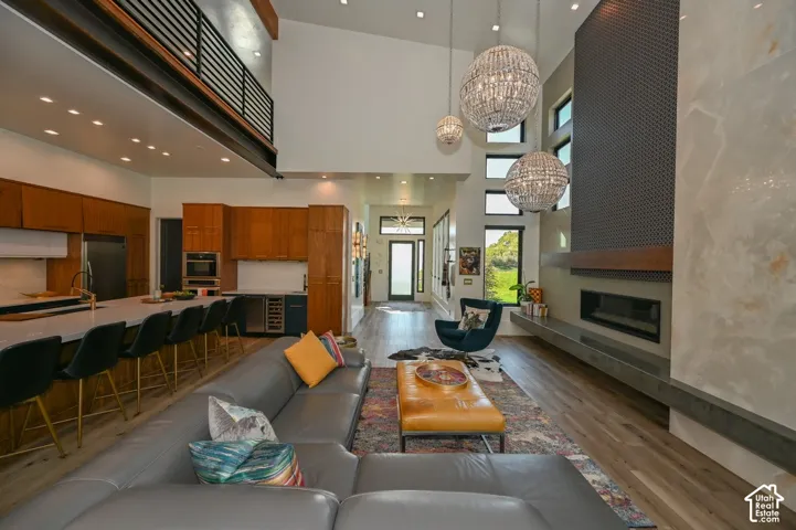Two-story ceiling, integrated kitchen with island seating, built-in fireplace, wood-finish flooring, and a second-story balcony
