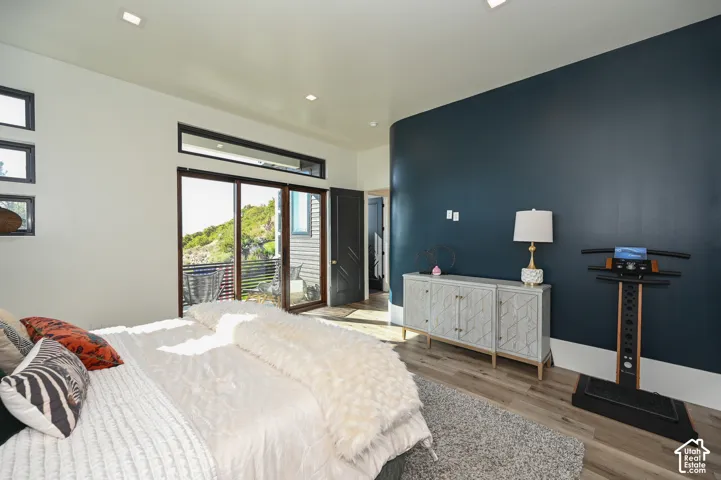 Room featuring wood-finish flooring, a contemporary dark accent wall, recessed lighting, and a glass sliding door providing access to an outdoor area