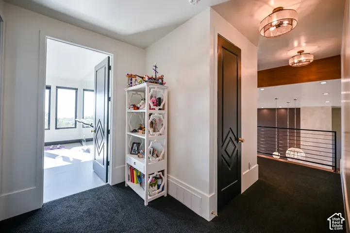 Hallway featuring dark carpeting and a built-in shelving unit