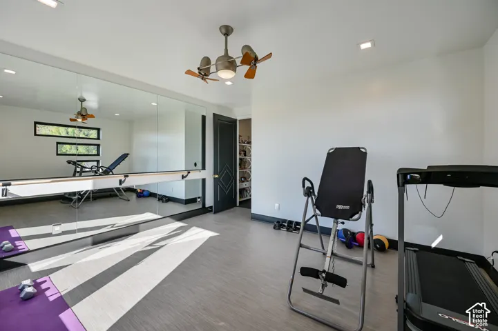 Dedicated fitness space featuring extensive mirrored walls, a built-in ballet barre, recessed lighting, and a ceiling fan